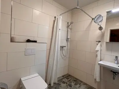 Helles Badezimmer mit Natursteinboden und ebenerdiger Dusche