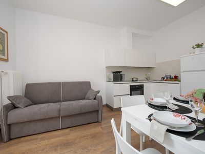 Wohnzimmer mit comfortablem Sofa, Esstisch und Küche