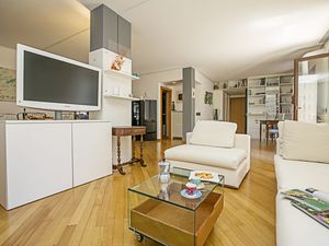 Das Wohnzimmer mit Sofa, Sessel, Couchtisch und großem Fernseher