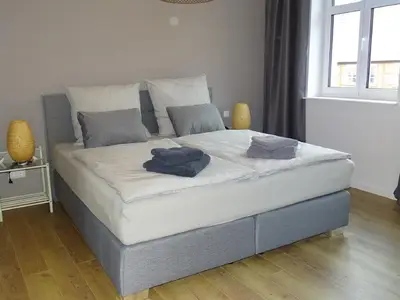 Schlafbereich. Modernes Schlafzimmer mit großem Boxspringbett und großem Kleiderschrank, Fenster mit 3-fach-Verglasung