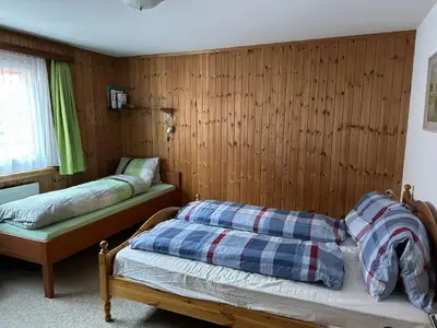 Zimmer mit Doppelbett und Einzelbett.