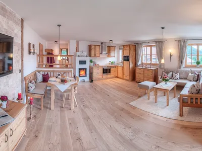 Wohnraum mit Ecksofa, Essgruppe, Kachelofen und Küche