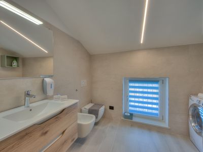 Badezimmer mit Hydromassage-Dusche, Waschbecken, Bidet, Toilette und Waschmaschine