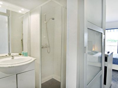 Das Badezimmer mit Duschkabine, Waschbecken mit Spiegel und Unterschrank, WC und Fön