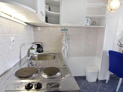 Die Küche mit Elektroherd mit zwei Kochplatten, Kühlschrank, Kaffeemaschine und Mokka.