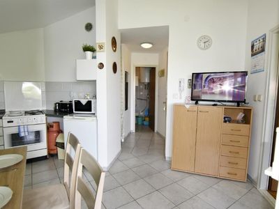 Der Eingang zum Wohnbereich mit Küche, Flachbildfernseher und Eingang zum Badezimmer