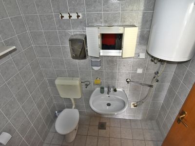 Das Badezimmer mit Dusche, WC, Waschbecken und Spiegel mit kleinem Schrank