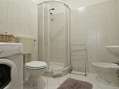 Das Badezimmer mit Dusche, Waschmaschine, Toilette, Bidet, Waschbecken, Spiegel mit Schrank und Haartrockner