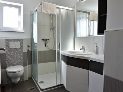 Das Badezimmer mit Dusche, WC, Waschbecken mit Spiegel, Schrank, Haartrockner