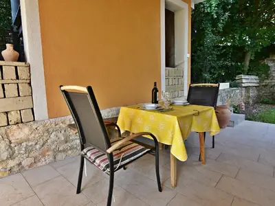 Die Terrasse des Rosemary Studios ist mit einem Esstisch und zwei Stühlen im Durchgang zum Pool ausgestattet