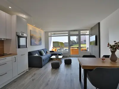 Strandkoje 105 Scharbeutz: Moderner Wohn- und Essbereich mit offener Küche und Zugang zum sonnigen Balkon.
