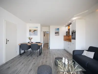 Strandkoje 105 Scharbeutz: Heller Wohn- und Essbereich mit moderner Küche und gemütlicher Couch.