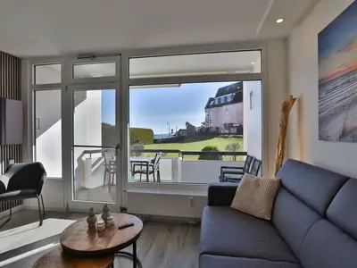 Strandkoje 106 in Scharbeutz – Wohnbereich mit großem Fenster und Zugang zum sonnigen Balkon.