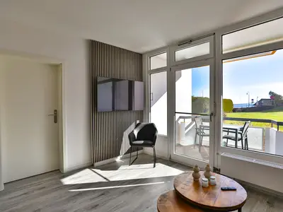 Strandkoje 104: Helles Wohnzimmer mit Blick ins Grüne und auf den Balkon in Scharbeutz.