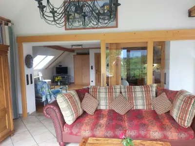 Blick vom Balkon in die zwei Wohnzimmerbereiche und rechts die Küche (hinter Glas)