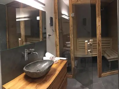 Badezimmer mit alpenländischer Design-Sauna und ebenerdiger Wellnessdusche