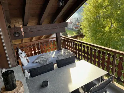 Gedeckter Balkon mit Tisch und Stühlen sowie Lounge Liege zur Entspannung