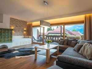 Wohnzimmer mit Doppelschlafcouch, TV und Sitzmöglichkeit, Zugang zu Terrasse und Balkon