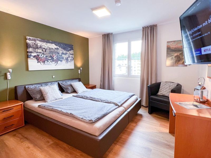 #1 Schlafzimmer: Großes Schlafzimmer mit SmartTV (inkl. Netflix-Zugang), Schreibtisch und Sessel. 