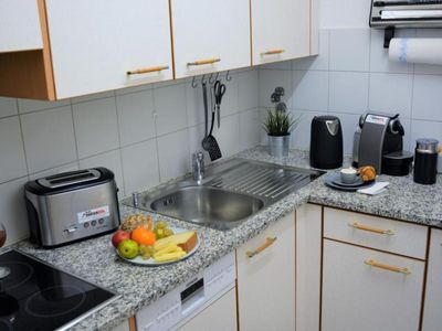 Funktionell eingerichtete Küche mit einer Arbeitsplatte aus Stein, Cerankochfeld, Spülmaschine. swissme holiday stmoritz