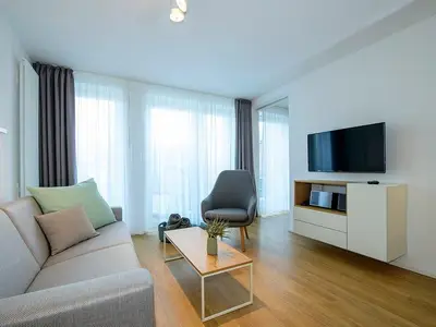 Wohn-Essbereich mit Couch, Couchtisch, Sessel und TV