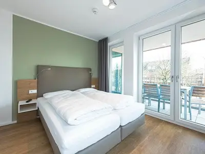 Schlafzimmer mit Doppelbett und Zugang zum Balkon
