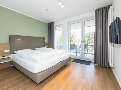 Schlafzimmer mit Doppelbett und Zugang zum Balkon