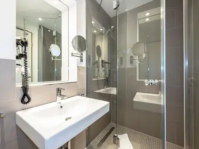 Badezimmer mit Dusche, WC, Waschtisch und Spiegel