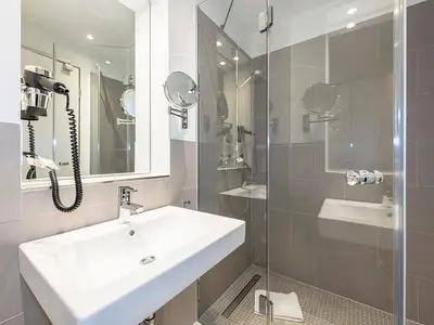 Badezimmer mit Dusche, Waschtisch, und Spiegel