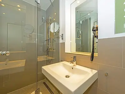 Badezimmer mit Dusche, Waschtisch, WC und Spiegel
