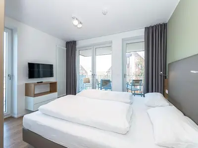 Schlafzimmer mit Zugang zum Balkon und TV