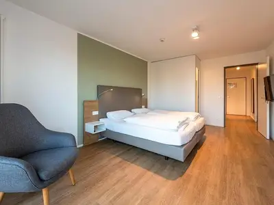 Schlafzimmer mit Boxspringbett, Sessel und TV