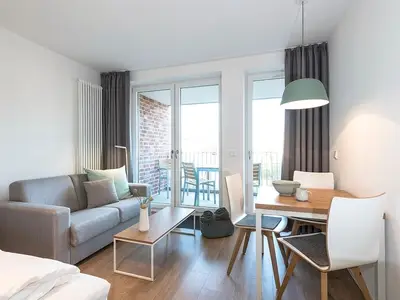 Wohnzimmer mit Schlafcouch, Esstisch mit  Zugang zum übertachten Balkon
