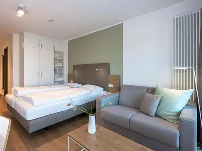 Wohnbereich mit Doppelschlafcouch, Kleiderschrank und Boxspringbett