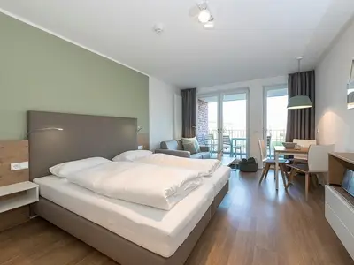 Wohnbereich mit Boxspringbett und Zugang zum überdachten Balkon