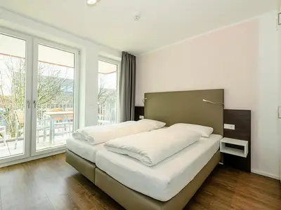 Schlafzimmer mit Doppelbett und Zugang zum Balkon