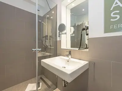Badezimmer mit Dusche, Waschtisch, WC und Spiegel