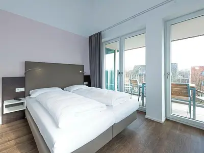 Schlafzimmer mit Doppelbett und Zugang zum überdachten Balkon