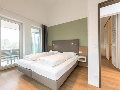 Schlafzimmer mit Doppelbett und Zugang zum überdachten Balkon