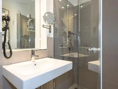 Badezimmer mit Dusche, Waschtisch, Fön und Spiegel