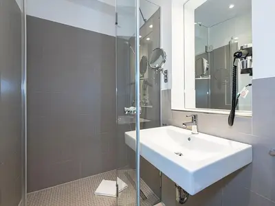 Badezimmer mit Dusche, Waschtisch, WC und Spiegel