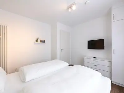 Schlafzimmer mit Doppelbett und TV
