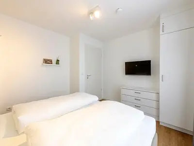 Schlafzimmer mit Doppelbett, Kleiderschrank und TV