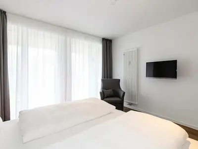 Schlafzimmer mit Doppelbett, Sessel und TV