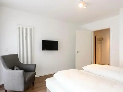Schlafzimmer mit Sessel, Doppelbett und TV