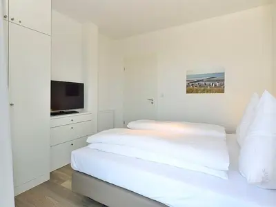 Schlafzimmer mit Doppelbett und Fernseher