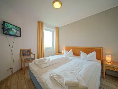 Schlafzimmer mit Doppelbett und TV