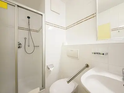 Badezimmer mit Dusche, Waschtisch, WC und Spiegel