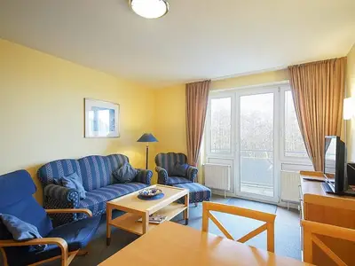 Wohnbereich mit Sofa, Sessel, Couchtisch und TV