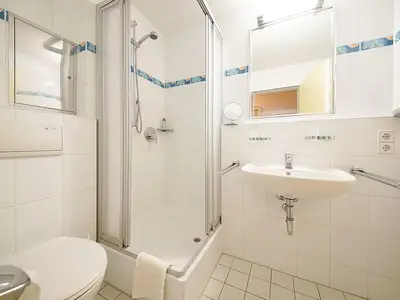 Badezimmer mit Dusche, WC, Waschtisch und Spiegel